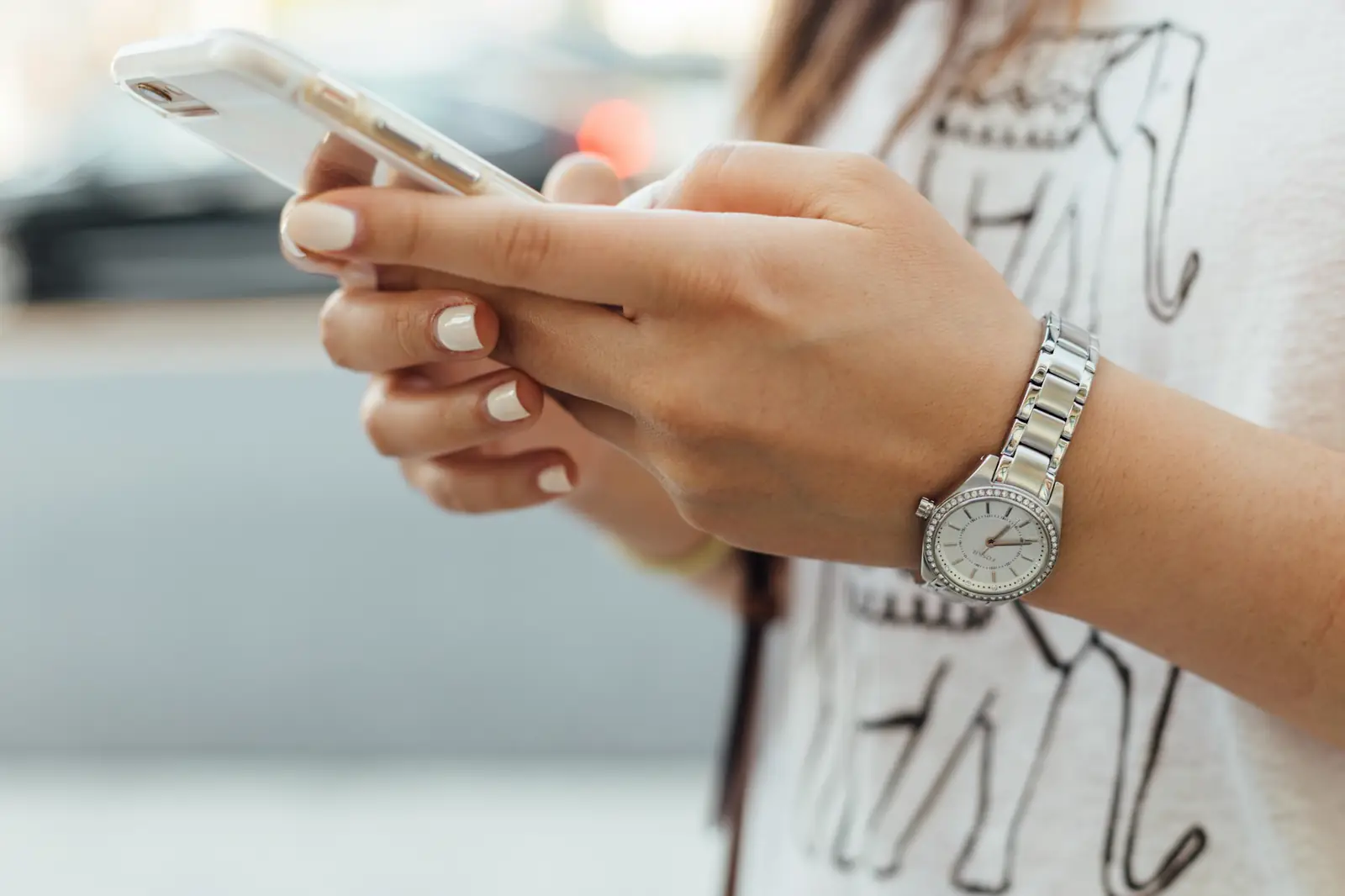 Las manos de una mujer escriben un mensaje en el celular.